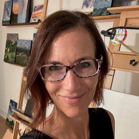 Artist Lisa Sims in an art studio with paintings on the wall